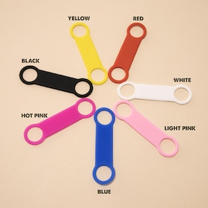 May include: Seven silicone strap holders in different colors: yellow, red, black, white, hot pink, light pink, and blue. Each strap holder has two loops.