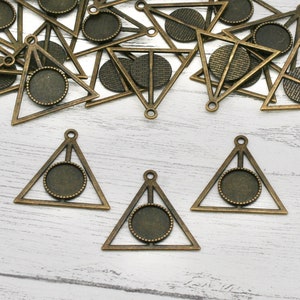 May include: A set of 10 antique gold triangle pendant trays with a circular opening in the center. The trays are perfect for creating unique jewelry pieces.