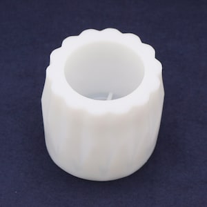 Può includere: Portacandele in ceramica bianca con un design scanalato. Il portacandele ha un'apertura rotonda nella parte superiore.