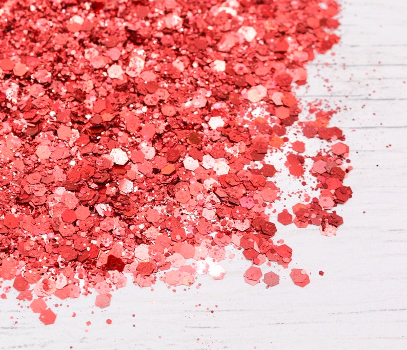 May include: A close-up of a pile of loose, sparkly, coral-colored glitter on a white surface.