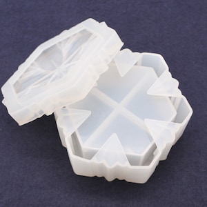 Pode incluir: Um molde de silicone hexagonal transparente com tampa, projetado para artesanato. O molde é dividido em quatro seções, com um design decorativo de estrela na tampa. As bordas têm um design ondulado.