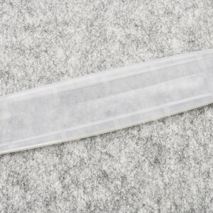 May include: A clear plastic rectangular box with a slightly textured surface.