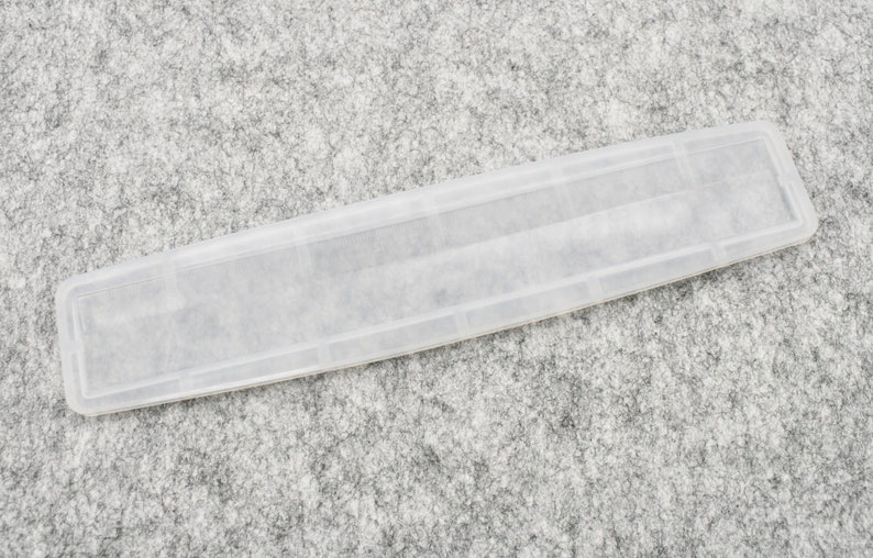 May include: A clear plastic rectangular box with a slightly textured surface.