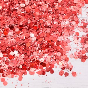 May include: A close-up of a pile of red glitter, scattered on a white surface.