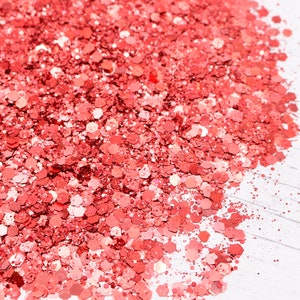 May include: A close-up of a pile of coral-colored glitter. The glitter is made up of small, hexagonal pieces.