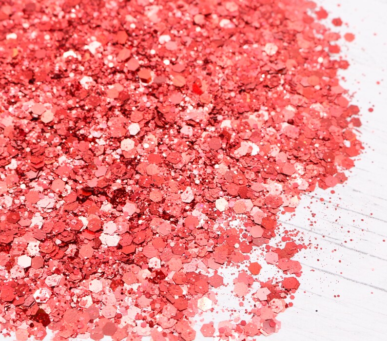 May include: A close-up of a pile of coral-colored glitter. The glitter is made up of small, hexagonal pieces.