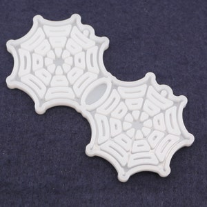 May include: White plastic mold in the shape of two connected spiderwebs. The mold is designed for making cookies or other treats.