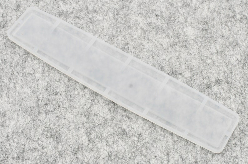 May include: A white plastic tile spacer with a rectangular shape and a smooth surface.