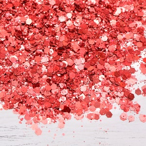 May include: A close-up of a pile of red glitter, with a white background.