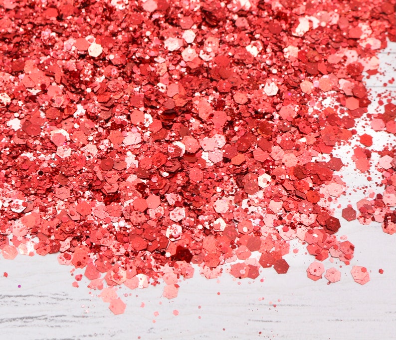 May include: A close-up of a pile of red glitter, with a white background.