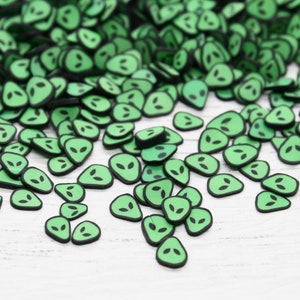Puede incluir: Sprinkles verdes en forma de cara de extraterrestre con contornos negros. Son ideales para decorar pasteles, cupcakes, galletas y otros productos horneados.