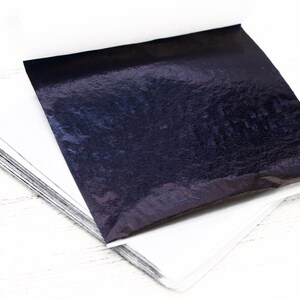 May include: A stack of thin, metallic sheets in a dark blue colour. The sheets are slightly wrinkled and have a subtle sheen.