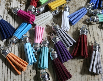 May include: Assortment of colorful suede tassels with silver metal tops. The tassels are various shades of blue, pink, red, orange, green, and gray.