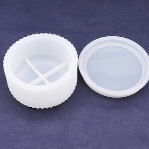 Könnte beinhalten: Runde weiße Silikonbehälter mit Deckel. Der Behälter hat vier Fächer im Inneren.