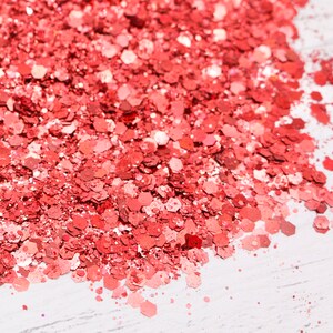 May include: A close-up of a pile of red glitter, with a white background.