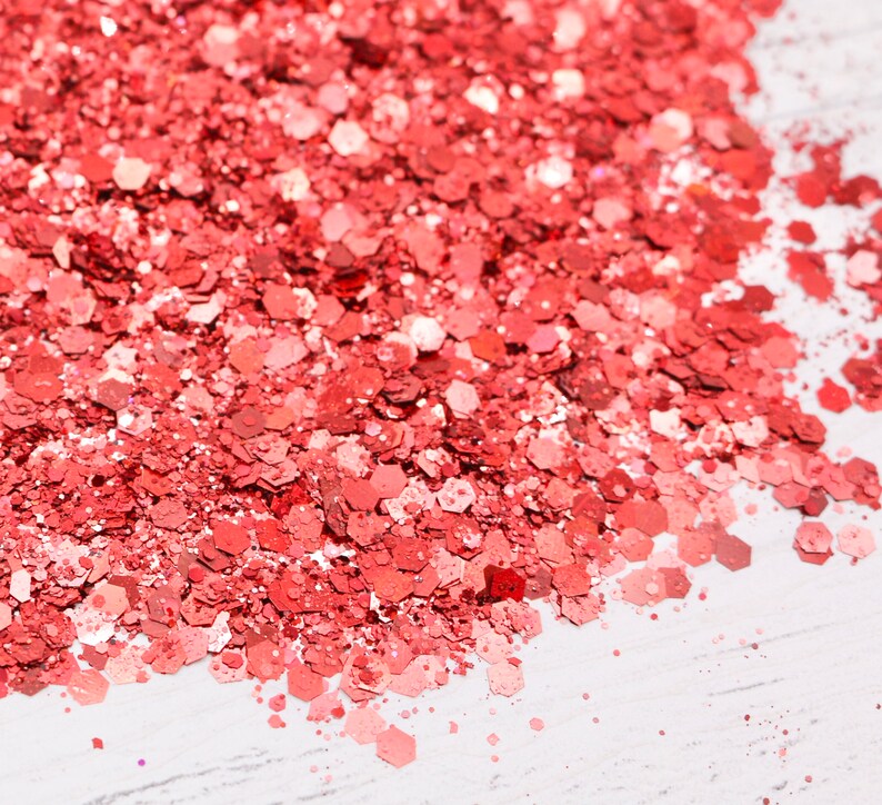 May include: A close-up of a pile of red glitter, with a white background.