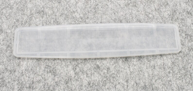 May include: A clear plastic storage case with multiple compartments. The case is designed to hold small items, such as jewelry, craft supplies, or medication.