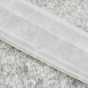 May include: A clear plastic ruler with black markings. The ruler is approximately 12 inches long.