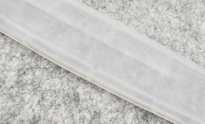 May include: A clear plastic ruler with black markings. The ruler is approximately 12 inches long.