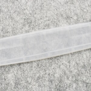 May include: A clear plastic tray with multiple compartments. The tray is designed to hold small items, such as jewelry or craft supplies.