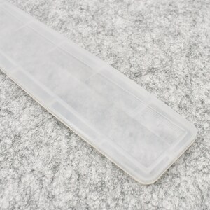 May include: A clear plastic ruler with a white background. The ruler has markings in inches.