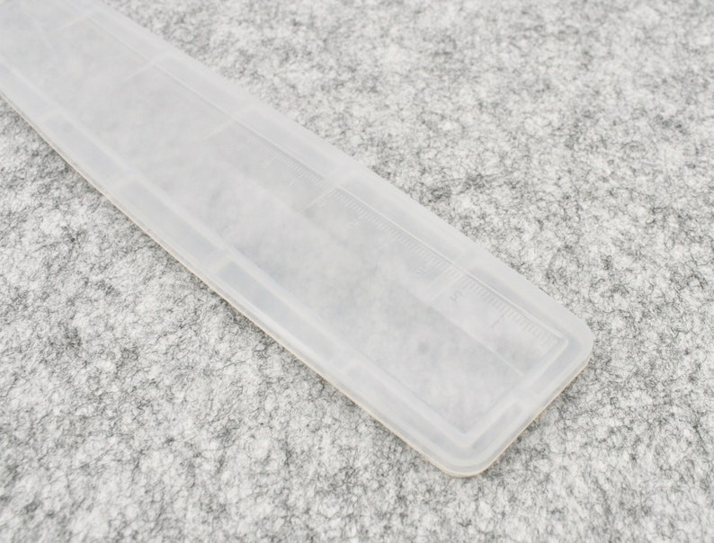 May include: A clear plastic ruler with a white background. The ruler has markings in inches.