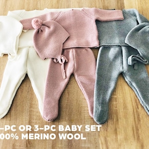 May include: Three knitted baby sets in white, pink, and gray. Each set includes a hat, a long-sleeved top, and pants. The sets are made of 100% merino wool. 2-PC OR 3-PC BABY SET 100% MERINO WOOL