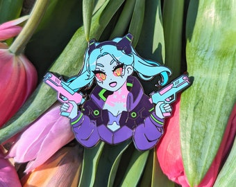 May include: A blue and purple enamel pin of a cartoon character with blue hair, holding two pink and blue guns. The character has a white and blue outfit with green accents.