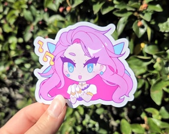 May include: A pink and blue cartoon sticker of a girl with long pink hair, blue eyes, and a star on her cheek. She is wearing a white and gold outfit and has a blue and white wing on her back. The sticker has a musical note design on the left side.