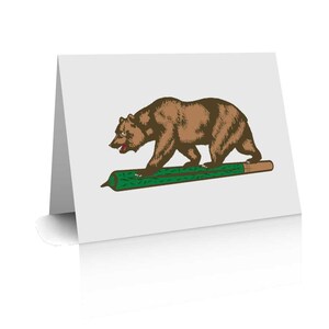 Puede incluir: Una tarjeta de felicitación con un oso marrón caminando sobre un tronco verde. El oso es el animal del estado de California.