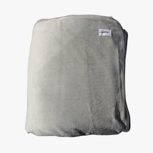 Puede incluir: Una manta de felpa gris con una etiqueta blanca que dice "Aero".