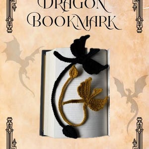 Puede incluir: Un marcapáginas de dragón tejido a ganchillo en negro y dorado sobre un libro abierto. El marcapáginas presenta dos extremos distintos con forma de dragón con alas y colas. El texto dice THE DRAGON BOOKMARK y Pattern By: Julianna Hussein.