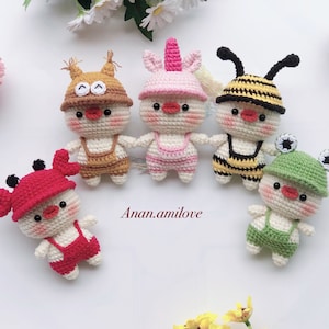 May include: Five crocheted stuffed animals dressed in different costumes. The animals are all white with red beaks and black eyes. The costumes include a crab, a unicorn, a bee, a squirrel, and a frog.