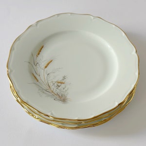 Peut inclure: Trois assiettes en porcelaine blanche avec un bord doré et un motif de blé brun.