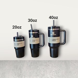 Puede incluir: Tres tazas de viaje Stanley de acero inoxidable negro con asas y tapas. Las tazas est&aacute;n etiquetadas como 20oz, 30oz y 40oz. Cada taza tiene una pajita.