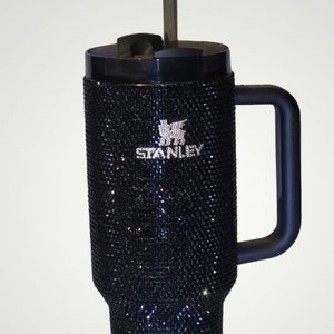 Puede incluir: Taza de viaje Stanley negra con asa negra y pajita transparente. La taza est&aacute; cubierta de pedrer&iacute;a negra y tiene el logotipo de Stanley en pedrer&iacute;a blanca.