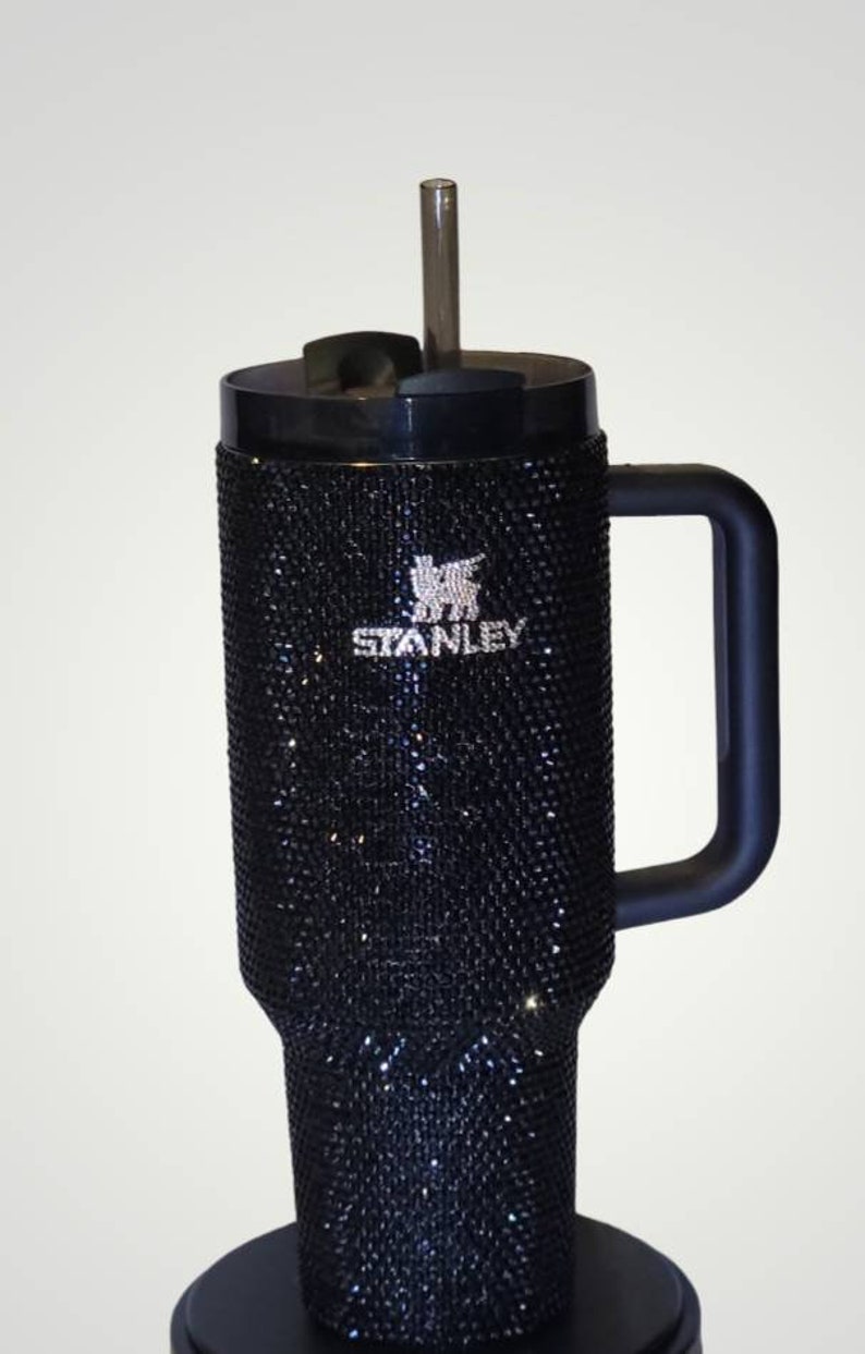 Puede incluir: Taza de viaje Stanley negra con asa negra y pajita transparente. La taza est&aacute; cubierta de pedrer&iacute;a negra y tiene el logotipo de Stanley en pedrer&iacute;a blanca.