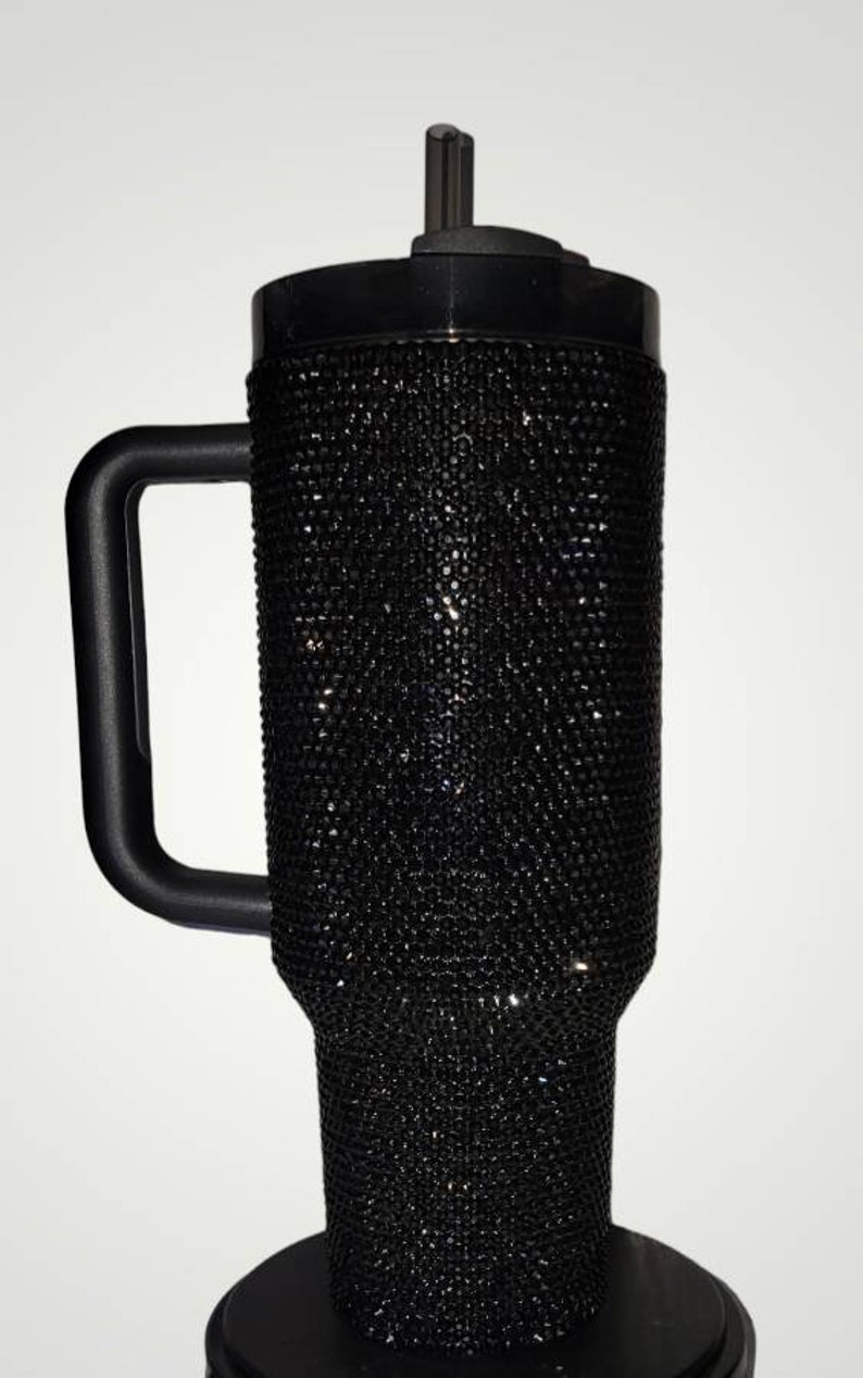 Puede incluir: Una taza de viaje negra con asa y tapa. La taza est&aacute; cubierta de diamantes de imitaci&oacute;n negros.