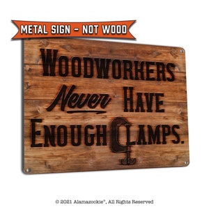May include: A rustic brown metal sign with a woodgrain texture. The sign reads "Woodworkers Never Have Enough Clamps."  A stylized image of a clamp is included in the text.