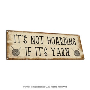 May include: A rustic wooden sign with the text "It's not hoarding if it's yarn" and two illustrations of yarn balls with knitting needles.