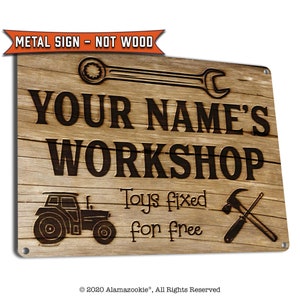 May include: A rustic brown metal sign with the text "YOUR NAME'S WORKSHOP" in black lettering. The sign also features a tractor, a wrench, a hammer, and a screwdriver, and the text "Toys fixed for free".