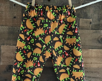 Peut inclure: Pantalon de survêtement noir avec un imprimé amusant de tacos, d'avocats et de sauce piquante.
