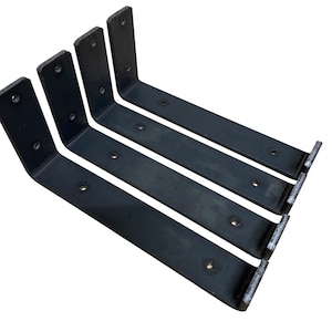 May include: Four black metal shelf brackets with multiple holes for mounting. The brackets are arranged in a staggered pattern, with the longest bracket at the bottom and the shortest bracket at the top.