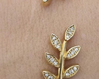 May include: Gold-toned bracelet featuring a leaf design with small, sparkling stones. The bracelet has a delicate, nature-inspired aesthetic, with a textured band. The leaves are adorned with clear, round gemstones.
