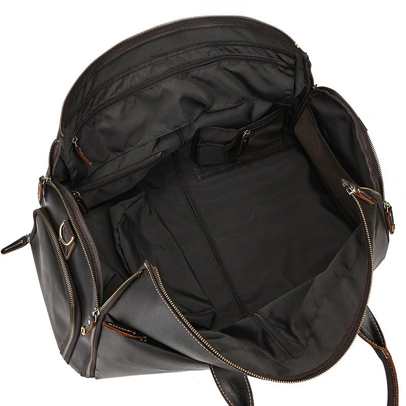 May include: Open view of a dark brown leather travel bag with multiple compartments and zippers. The bag has a large main compartment and several smaller pockets for organization. The interior is lined with a dark fabric.