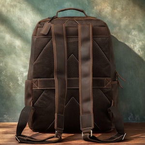 Pode incluir: Uma mochila de couro marrom com al&ccedil;as ajust&aacute;veis e uma al&ccedil;a superior. A parte de tr&aacute;s da mochila tem um design de malha respir&aacute;vel. A bolsa tem fecho de z&iacute;per e uma pequena etiqueta de couro.