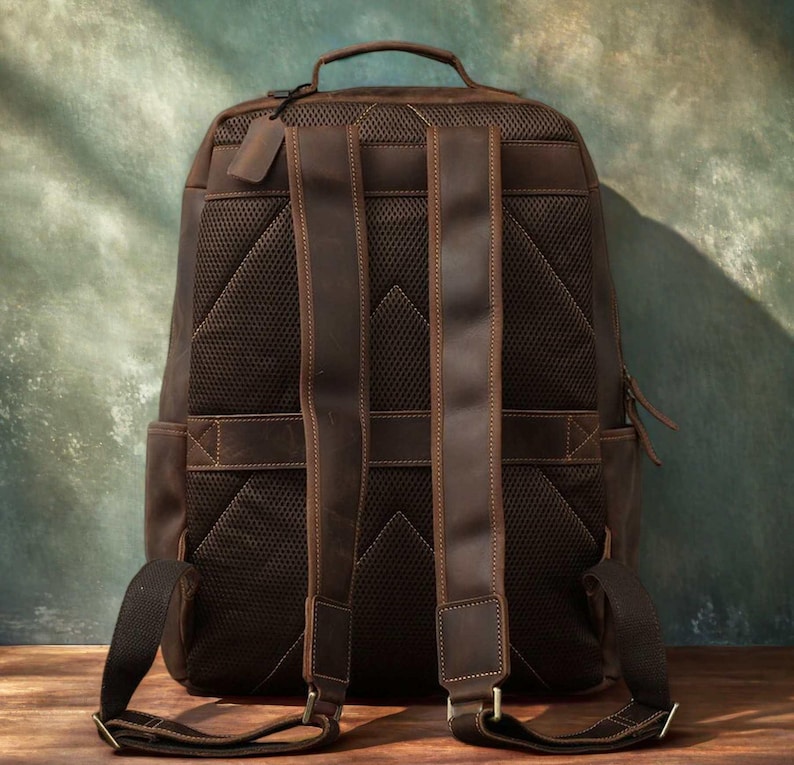 Pode incluir: Uma mochila de couro marrom com al&ccedil;as ajust&aacute;veis e uma al&ccedil;a superior. A parte de tr&aacute;s da mochila tem um design de malha respir&aacute;vel. A bolsa tem fecho de z&iacute;per e uma pequena etiqueta de couro.