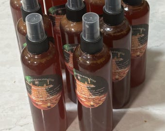 May include: A group of eight amber glass spray bottles with black tops and labels that say "creationscometrue" and "lemonade fizz water" on them. The bottles are arranged in a semi-circle on a white surface.