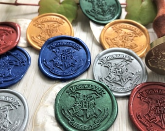May include: A collection of colorful wax seals with the Hogwarts crest. The seals are in various colors, including gold, blue, green, silver, and red. The seals are round and embossed with the Hogwarts crest and the words "Hogwarts" and "Draco Dormiens Nunquam Titillandus".