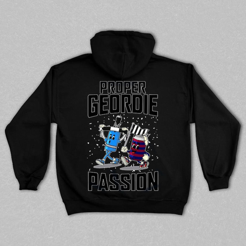 以下が含まれることがあります： 黒色のパーカー。白文字で「PROPER GEORDIE PASSION」と書かれています。背面には、旗を持った2人の漫画のキャラクターのイラストが描かれており、1人は青色、もう1人は赤と青色です。